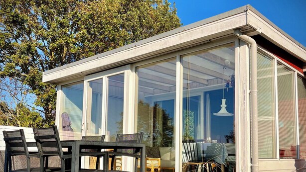 A conservatory with a table and chairs, a potted plant, and a view of the outdoors.