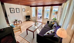Ein Wohnzimmer mit einer Couch, einem Couchtisch, einem Fernseher und einem Kamin.