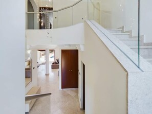 Un interior moderno con una escalera, una puerta de madera y una sala de estar con sofá.