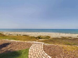 Un camino pavimentado que conduce a una playa con vista despejada al océano.