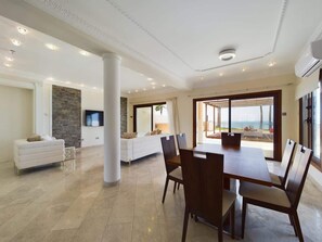 A spacious living area with a dining table, sofas, and a stone accent wall. - Fabulous Beach Front House (Perivolia)