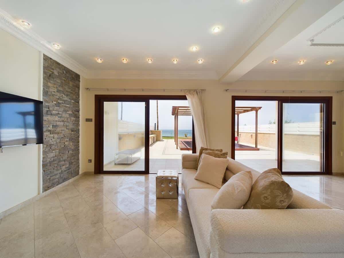 A spacious living room with a sofa, a television, and a stone wall.