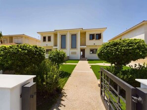 A building with a central entrance, surrounded by greenery and a pathway leading to it. - Fabulous Beach Front House (Perivolia)