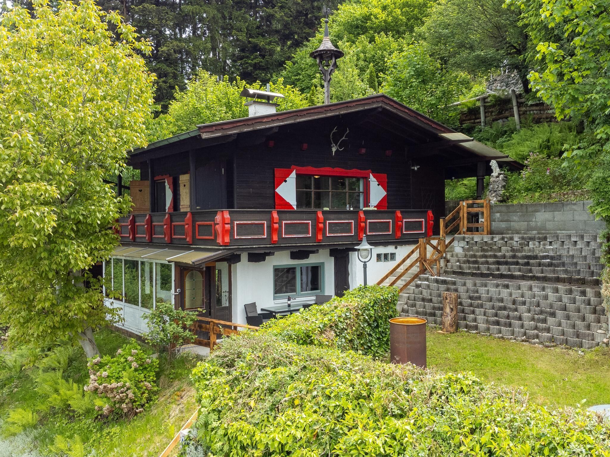 A two-story building with a balcony, a stone wall, and a staircase leading to the upper level.