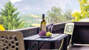 Ein Tisch mit einer Flasche, Gläsern, Trauben und Blick auf Berge.