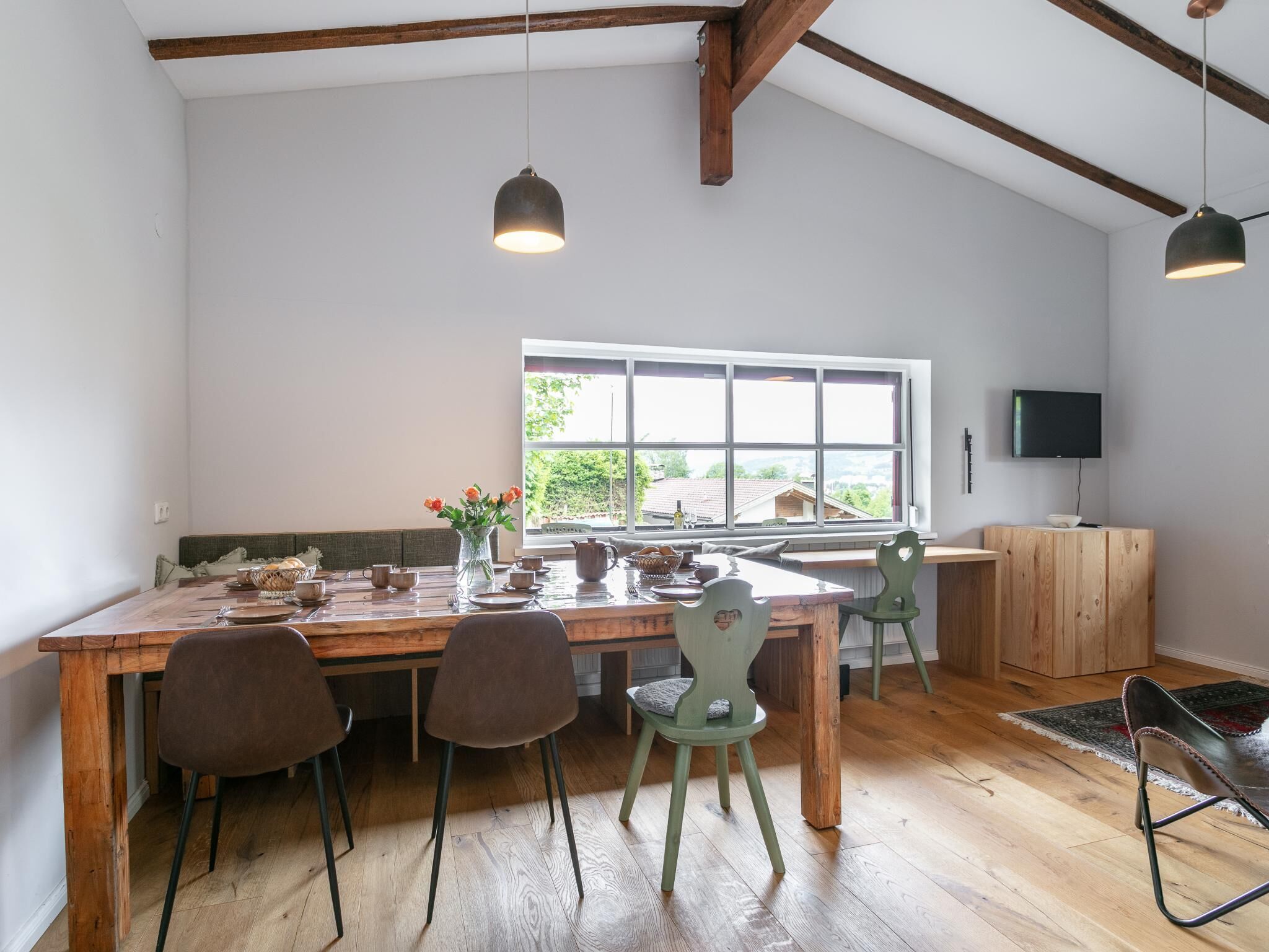 A dining area with a wooden table, chairs, and a window with a view.