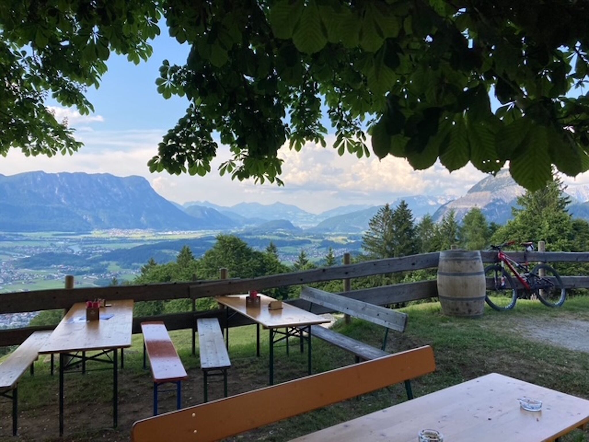 A picnic area with benches and tables, a bicycle, and a view of mountains.