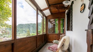 Ein Zimmer mit Holzwänden, einem großen Fenster, einem Stuhl und einem kleinen Tisch.