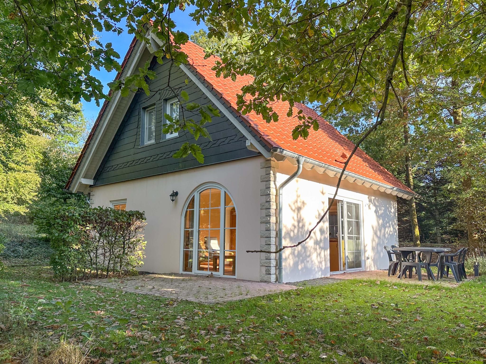 A house with a sloped roof, a large arched window, and a stone foundation.