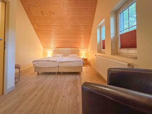 A bedroom with a wooden ceiling, a double bed, bedside lamps, a radiator, and a window with blinds. - Luxury detached home with garden and sauna (Brandscheid)