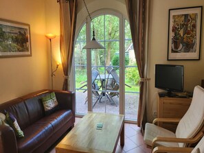 Ein Wohnzimmer mit einer Ledersofa, einem Holztisch, einem Fernseher und einem Essbereich mit Stühlen und Tisch.