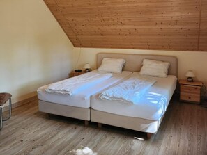 Ein Doppelbett mit Holz-Kopfteil, zwei Nachttische jeweils mit Lampen und ein Holzboden.