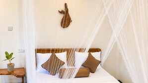 A bed with a canopy, a wooden headboard, and a wall-mounted decorative piece. - Serenity Cottage (Ella)