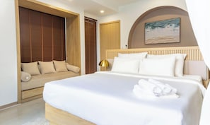 Quarto de hotel com cama, sofá, guarda-roupa de madeira e um quadro na parede.