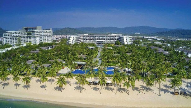 Un resort con varias edificaciones, playa y palmeras.