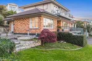 A two-story house with a brick facade, large windows, and a balcony. - Lake View Apartment with parking (Hamilton)
