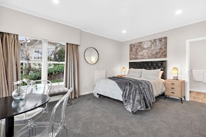A bedroom with a bed, bedside tables, a desk, and a window. - Lake View Apartment with parking (Hamilton)