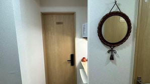 Ein Korridor mit einer Holztür mit der Aufschrift '201', einer weißen Wand und einem Spiegel mit dekorativem Rahmen.