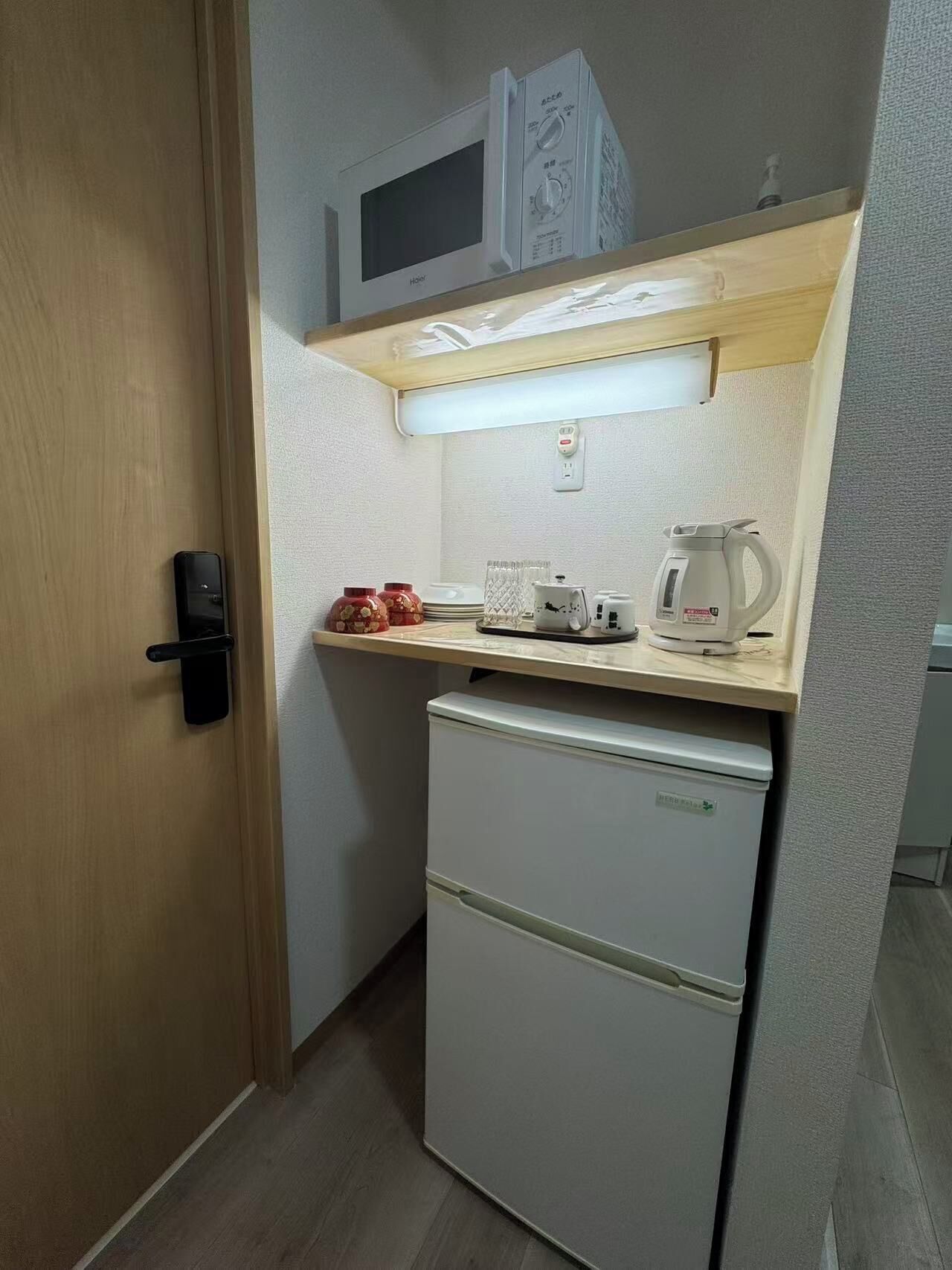 A compact kitchenette with a microwave, a small refrigerator, a kettle, and a toaster.
