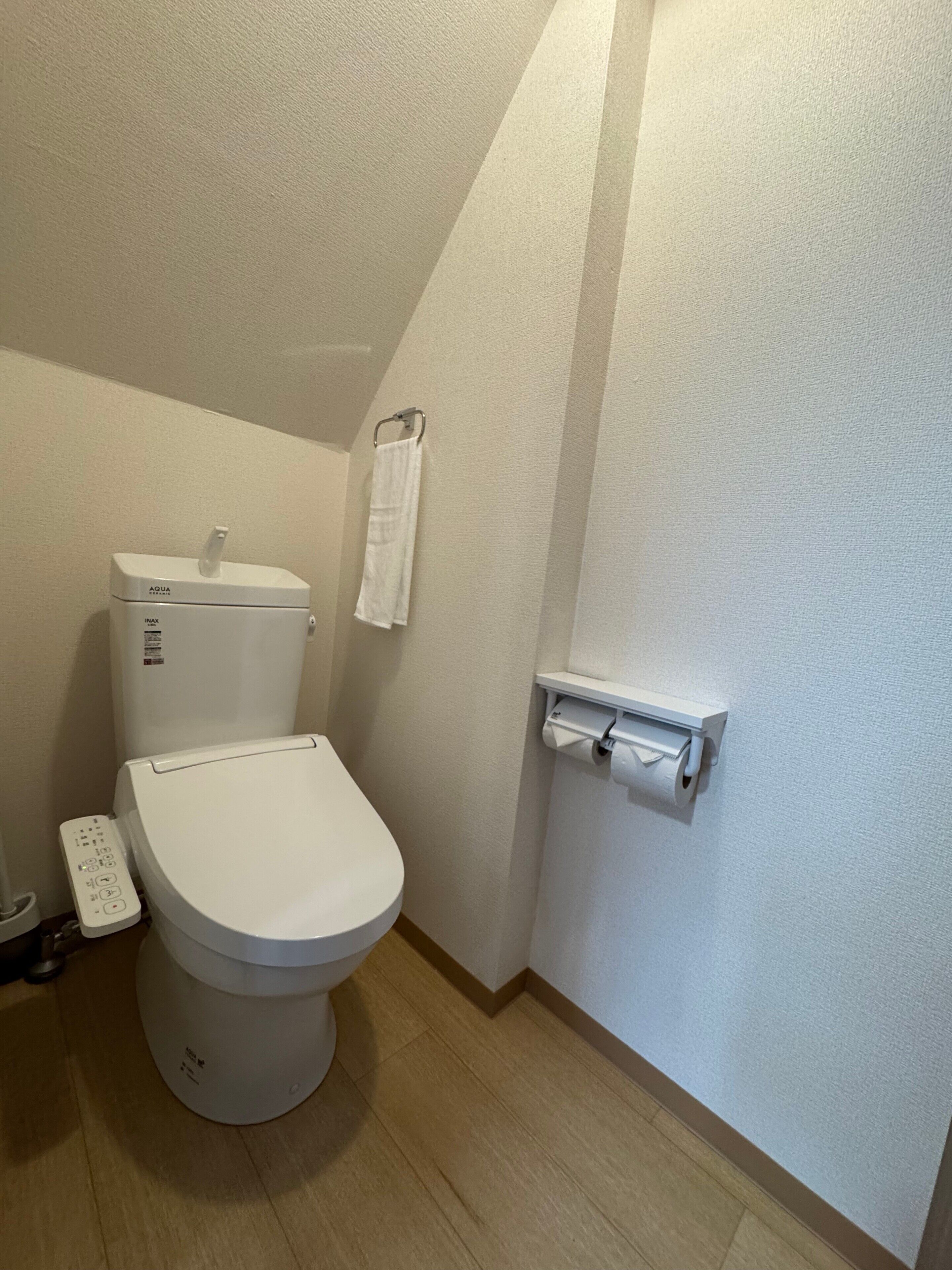 A small, clean bathroom with a toilet, a hand dryer, and a paper towel dispenser.