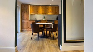 A kitchen with wooden cabinets, a dining table with chairs, and a large mirror. - The Forest Green Residence – Garden & Tranquility (Oldenburg)