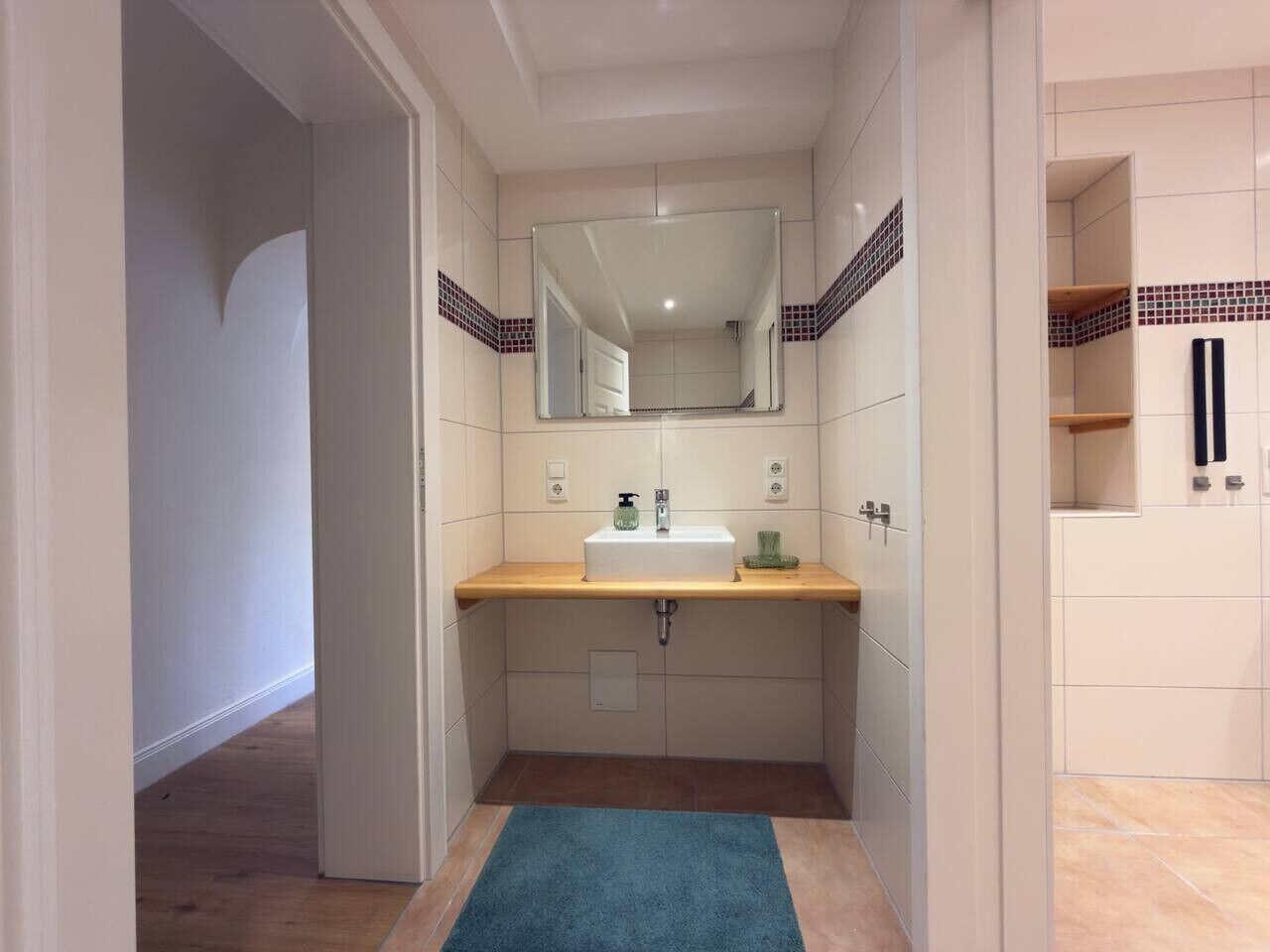 A compact bathroom with a sink, mirror, and storage cabinets.