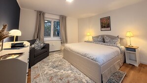 Une chambre à coucher comprenant un lit, des tables de chevet, une fenêtre, un radiateur et un tableau accroché au mur.