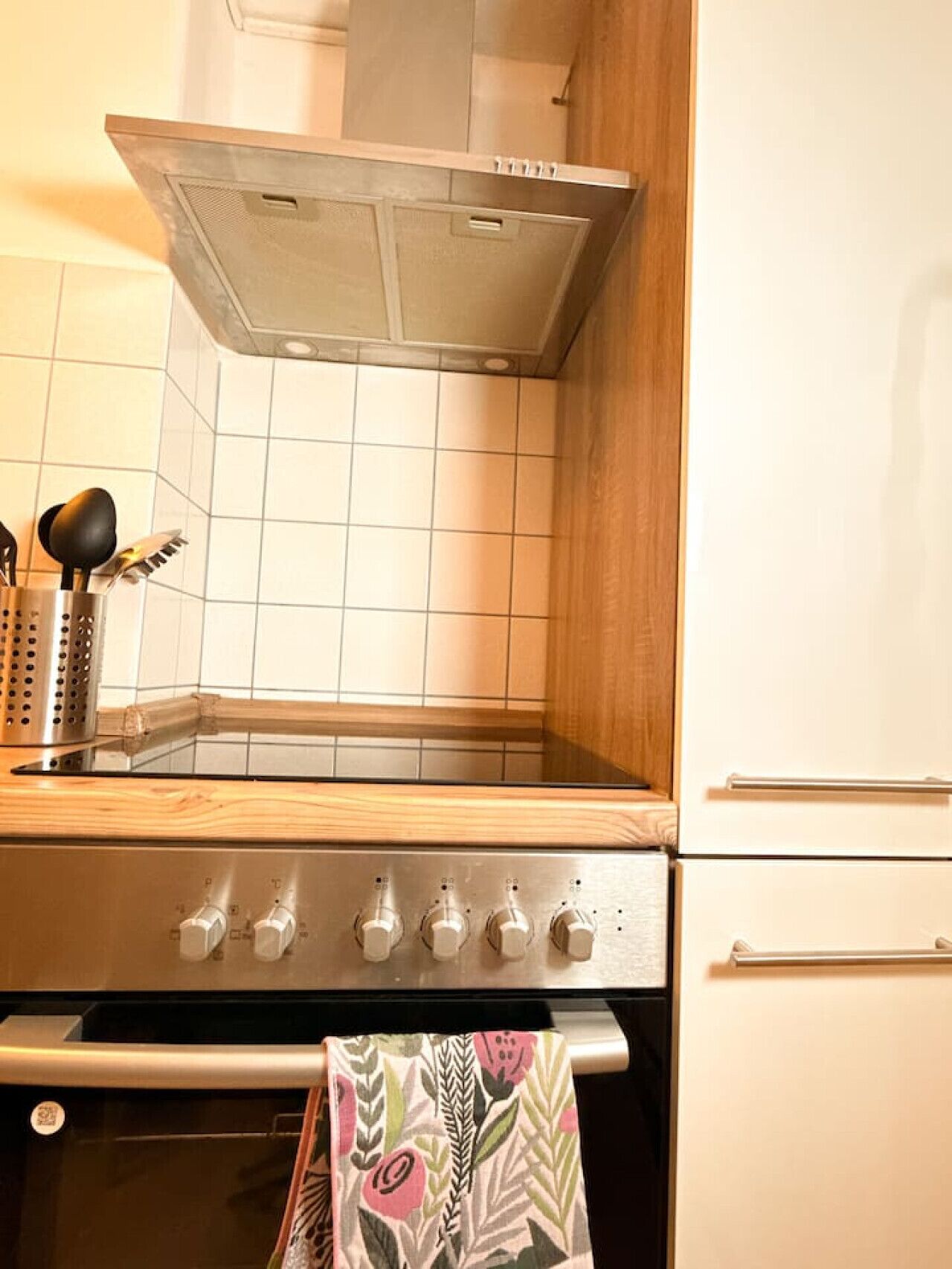 Eine Küche mit Edelstahlbackofen, Dunstabzugshaube und Fliesenrückwand.