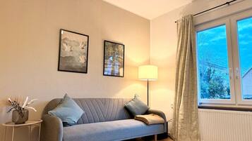 A living room with a sofa, a lamp, and a window with curtains.