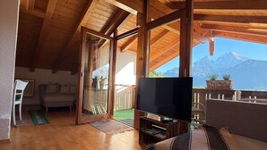 Un intérieur en bois avec un téléviseur, un canapé et une vue sur les montagnes.