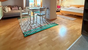 Une pièce mansardée chaleureuse avec un plafond en bois, une table à manger avec des chaises, un canapé et un lit.