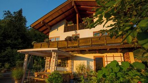 Un chalet traditionnel doté d’un balcon en bois, d’une terrasse couverte et de plantes en pot.