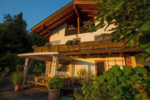 Ein traditionelles Chalet mit Holzbalkon, überdachter Terrasse und Blumentöpfen.