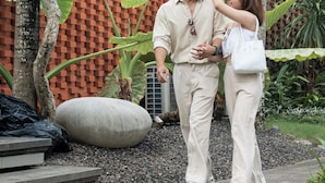 A couple standing in a garden with a brick wall and tropical plants. - Serenity Villa Nusa Dua (Badung)