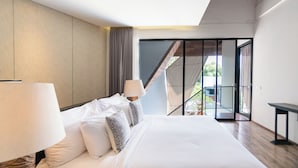 A modern hotel room with a large bed, a balcony with a view, and a sliding glass door. - Serenity Villa Nusa Dua (Badung)