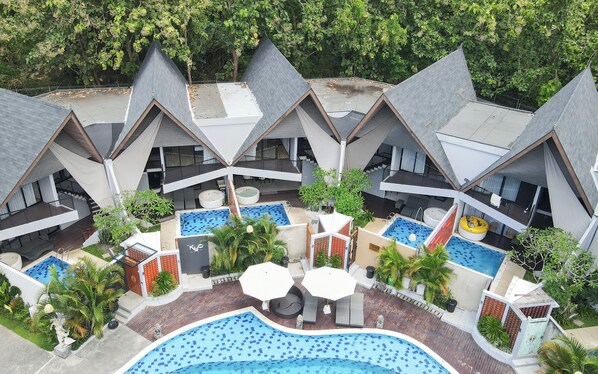 A resort with multiple triangular-roofed buildings, a central swimming pool, and various outdoor seating areas. - Serenity Villa Nusa Dua (Badung)