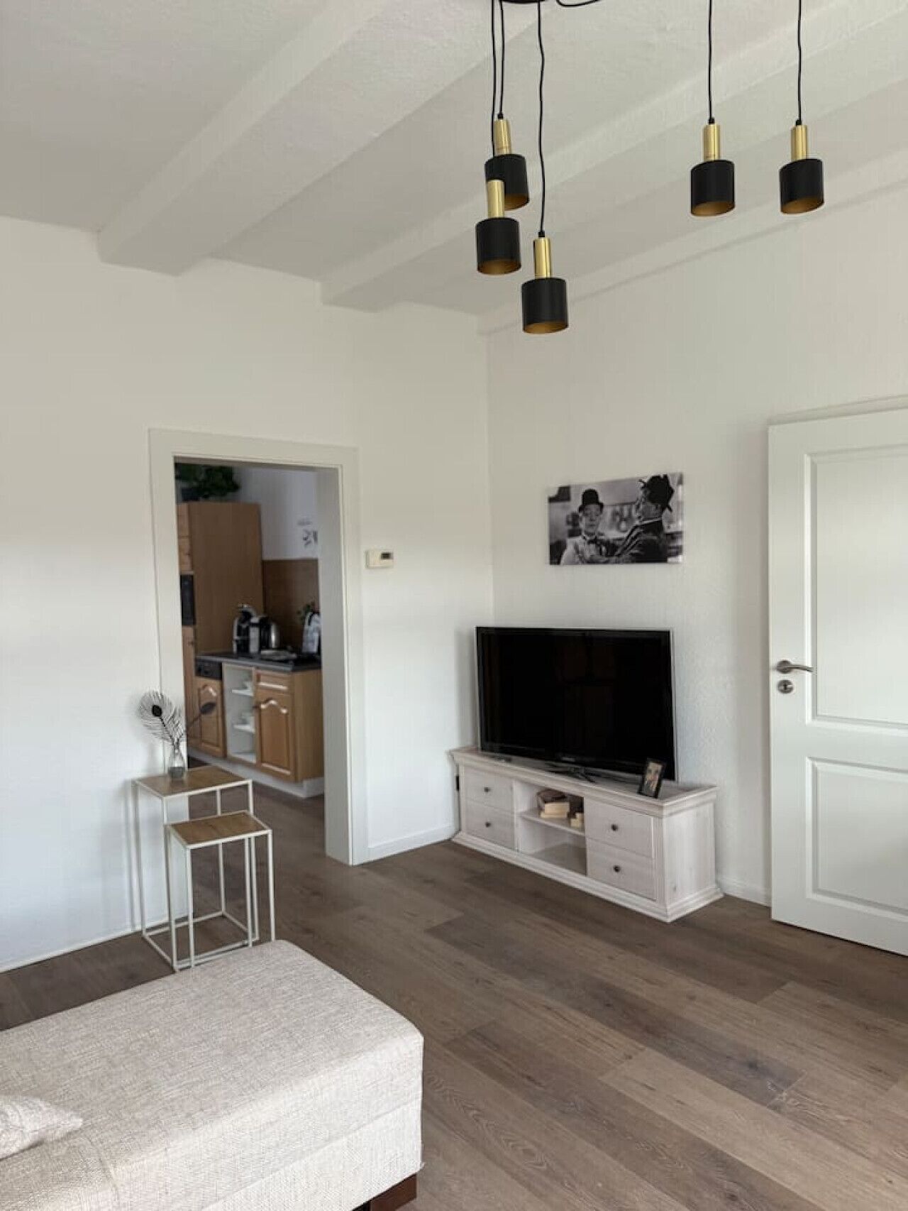 Un salon moderne avec un téléviseur à écran plat, un meuble blanc, une petite table et un banc.