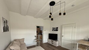 Un salon avec un canapé, un téléviseur et une porte donnant sur la cuisine.