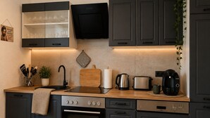Eine moderne Küche mit dunklen Schränken, einem Einbauofen, einer Kaffeemaschine und einem Toaster.