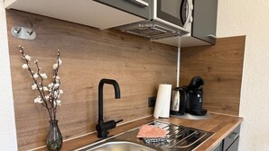 Una cocina moderna con un lavamanos de acero inoxidable, grifo negro, encimera de madera y cafetera.