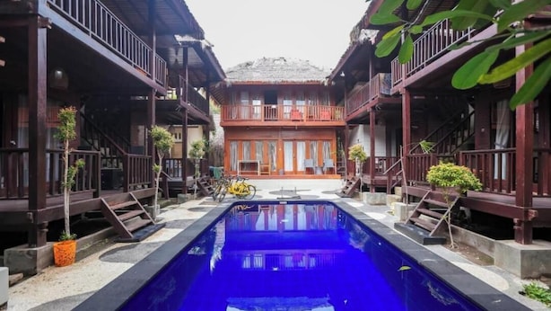 A traditional wooden building with a central pool, surrounded by smaller structures. - CJs Bungalow (Gili Trawangan)