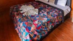 A wooden room with a bed, an air conditioning unit, and a painting on the wall. - CJs Bungalow (Gili Trawangan)