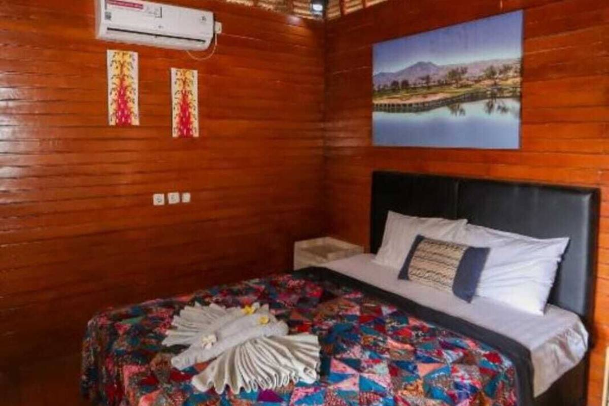 A wooden room with a bed, an air conditioning unit, and a painting on the wall.