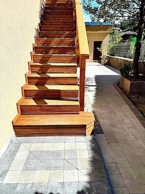 Eine Holztreppe mit Handlauf, die zu einem Hauseingang führt.