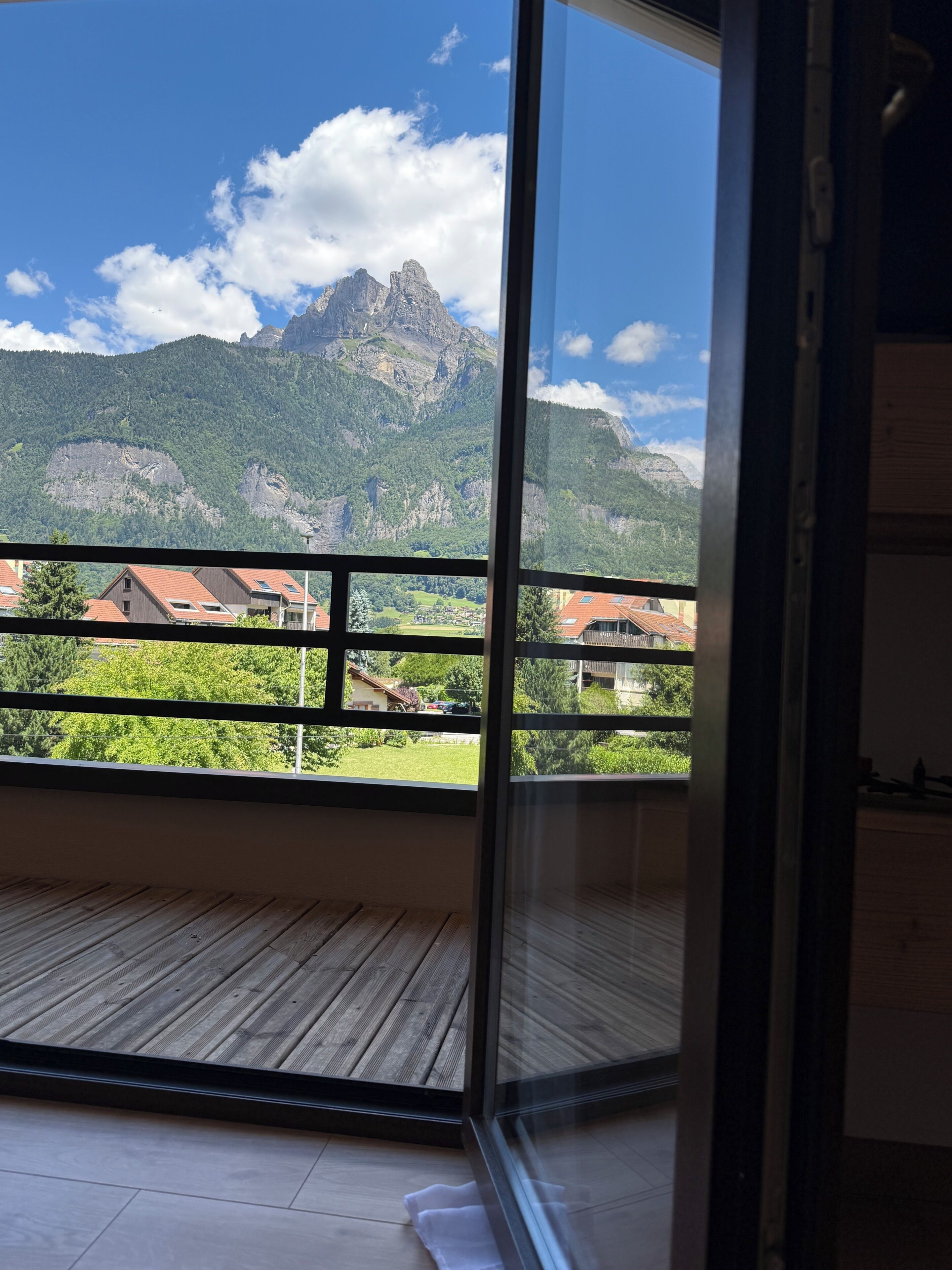 En balkon med udsigt til bjerge, trægulv og en glasdør.