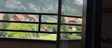 En balkong med utsikt över bergen, ett trägolv och en glasdörr.
