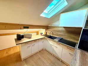 Eine kompakte Küche mit Oberlicht, Holz Arbeitsplatte und weißen Schränken.