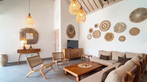 Un salon comprenant un canapé, des fauteuils, une table basse, un téléviseur et des éléments de décoration murale.