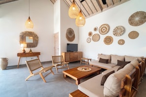 Ein Wohnzimmer mit Sofa, Sesseln, Couchtisch, Fernseher und Wanddekoration.