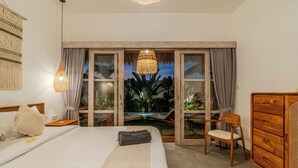 Une chambre avec un lit, une commode en bois, une chaise, une fenêtre avec des rideaux et une vue sur une piscine et la verdure.